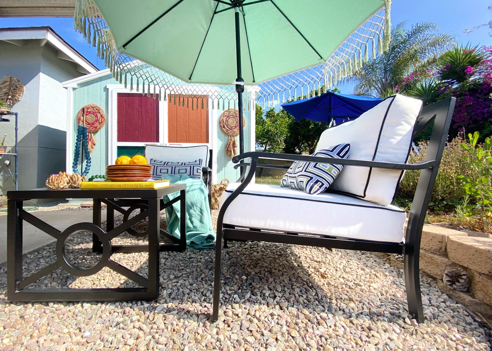 A view of the kathy ireland Homes and Gardens Madison Ave. outdoor collection styled by Rachel Moriarty in front of a she shed with a multi-colored door.