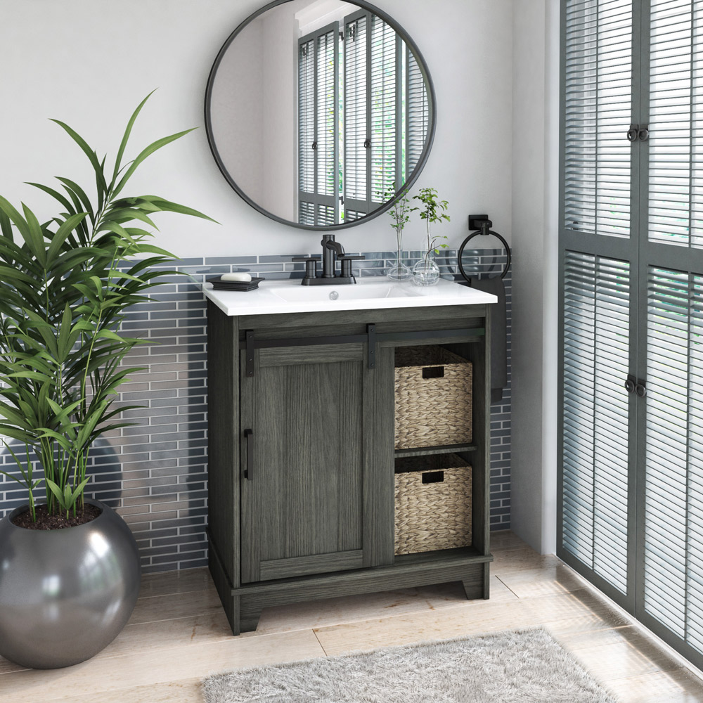 A rustic finished single sink bathroom vanity with a sliding barn door and two baskets on open front shelves in a bathroom with gray accents