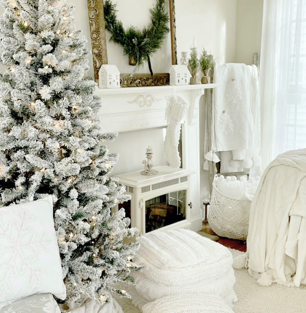 A white duraflame electric fireplace stove heater in a white modern farmhouse room next to a snow-flocked Christmas tree